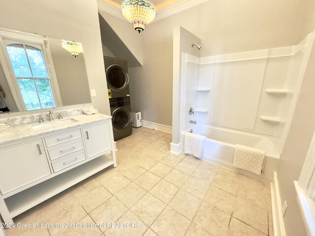 bathroom featuring vanity, stacked washing maching and dryer, tile patterned flooring, ornamental molding, and washtub / shower combination