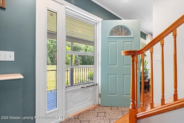 entrance foyer featuring wood-type flooring, ornamental molding, and a wealth of natural light