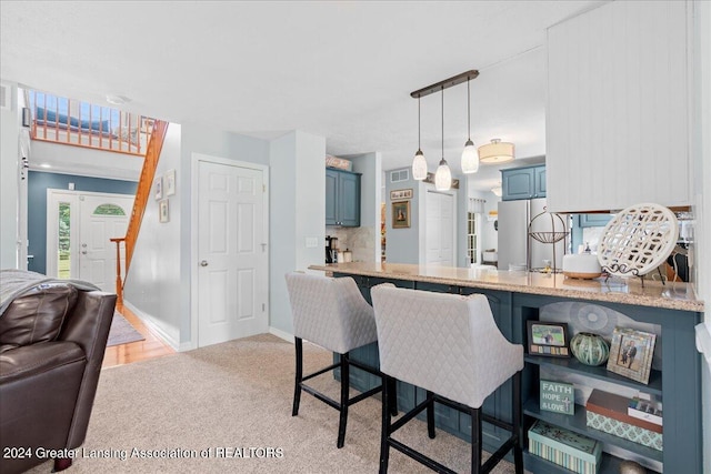 kitchen featuring backsplash, kitchen peninsula, pendant lighting, blue cabinetry, and light colored carpet