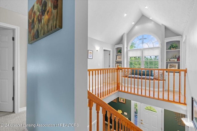 hallway featuring light carpet, lofted ceiling, and a textured ceiling