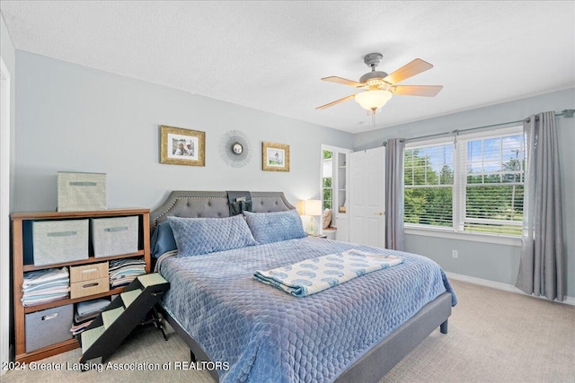 bedroom with light carpet, ceiling fan, and a textured ceiling