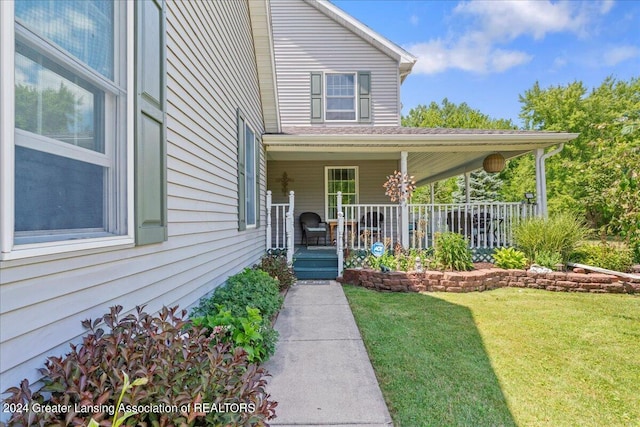 entrance to property with a porch and a lawn