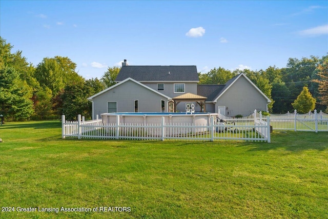 back of property with a lawn and a fenced in pool