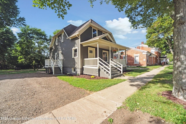 view of front of home with covered porch and a front lawn