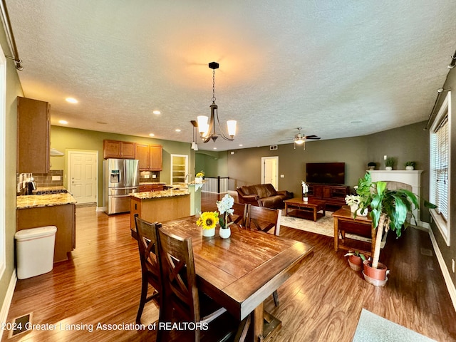 dining room with a textured ceiling, hardwood / wood-style floors, ceiling fan with notable chandelier, and sink