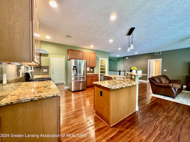 kitchen featuring decorative light fixtures, hardwood / wood-style flooring, stainless steel appliances, and a textured ceiling