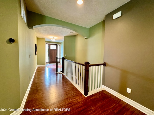 corridor featuring a textured ceiling and dark hardwood / wood-style floors