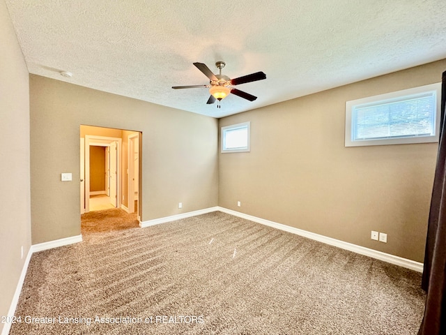 carpeted spare room with a textured ceiling and ceiling fan