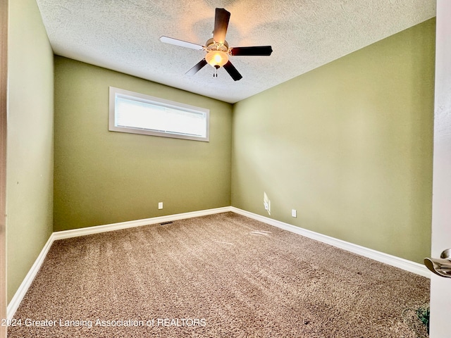 carpeted spare room featuring ceiling fan and a textured ceiling