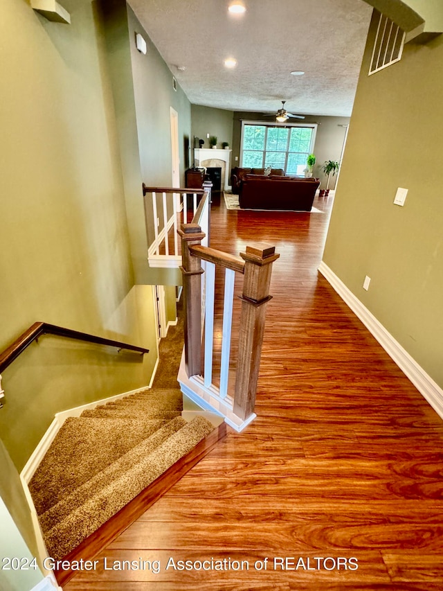 stairs featuring a textured ceiling, ceiling fan, and wood-type flooring