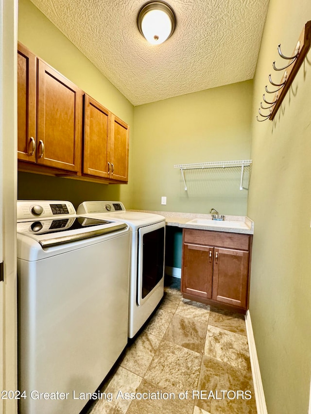 laundry area featuring a textured ceiling, cabinets, and washer and dryer