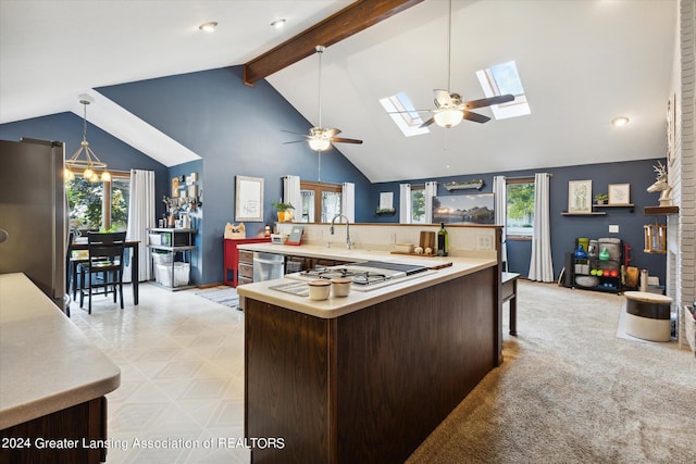 kitchen featuring a skylight, stainless steel appliances, beamed ceiling, kitchen peninsula, and ceiling fan