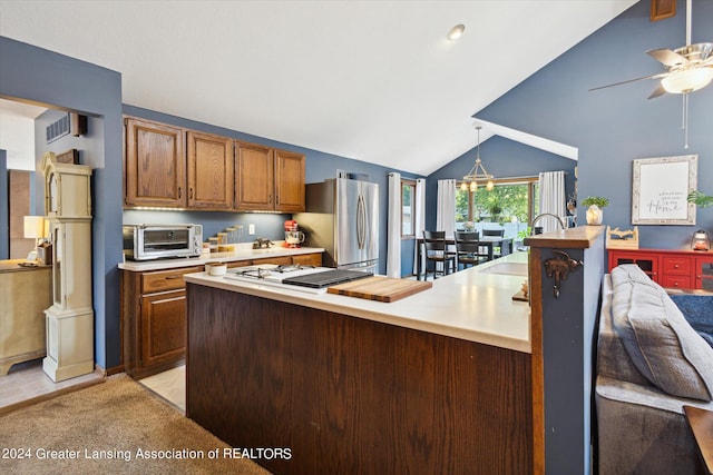 kitchen featuring vaulted ceiling, light tile patterned floors, hanging light fixtures, stainless steel refrigerator, and ceiling fan