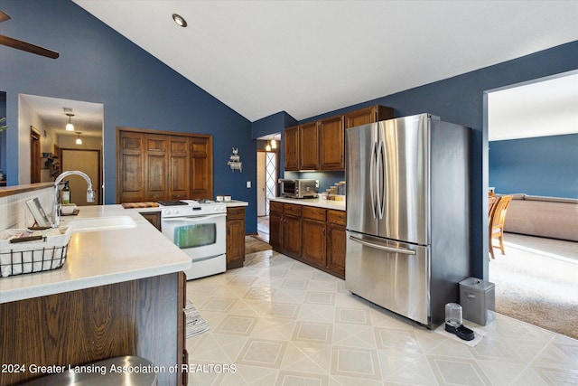 kitchen featuring vaulted ceiling, white stove, sink, stainless steel fridge, and ceiling fan