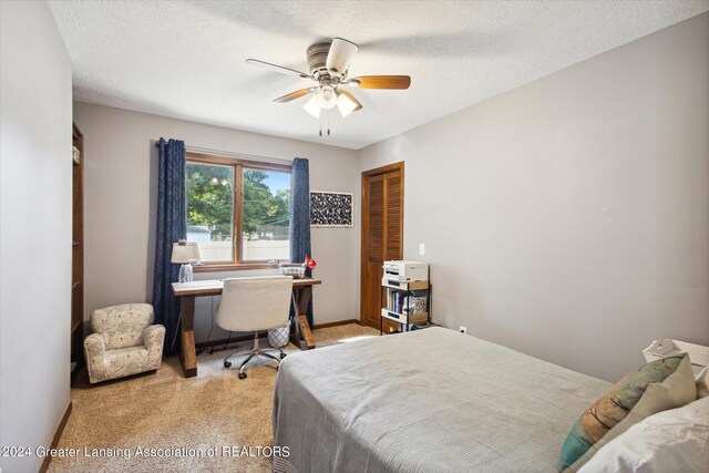 carpeted bedroom with a textured ceiling, ceiling fan, and a closet