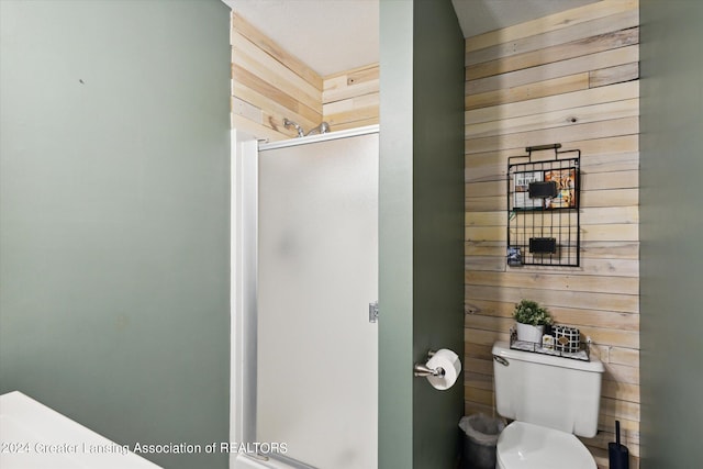 bathroom with toilet, wooden walls, and a shower with door