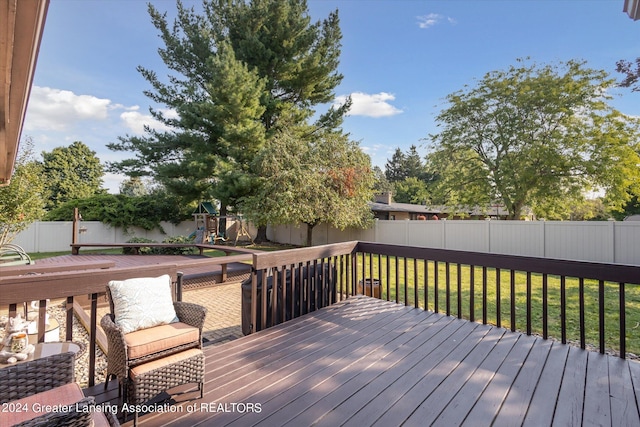 wooden deck with a playground and a yard