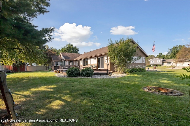 rear view of property with a fire pit, a yard, and a wooden deck