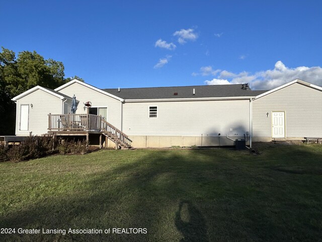 back of house with central air condition unit, a deck, and a lawn