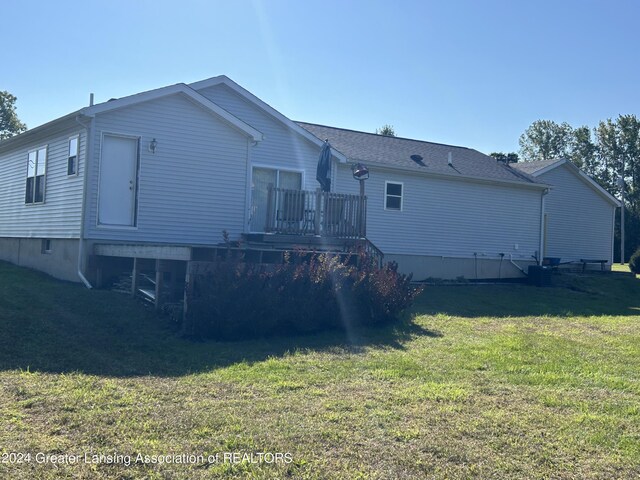 rear view of property featuring a wooden deck and a yard