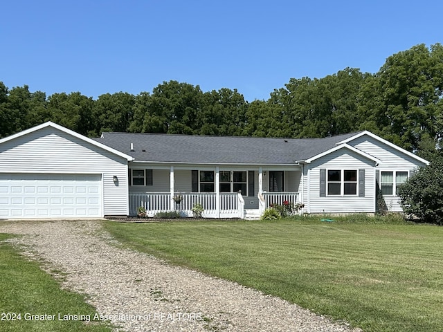 ranch-style home featuring covered porch, a garage, and a front yard