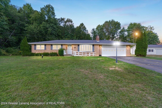 single story home with covered porch, a yard, and a garage