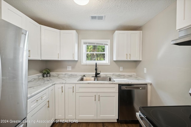 kitchen with white cabinets, appliances with stainless steel finishes, light stone countertops, sink, and dark hardwood / wood-style floors