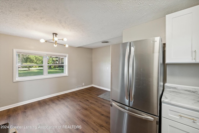 kitchen with a notable chandelier, white cabinetry, dark hardwood / wood-style flooring, stainless steel fridge, and light stone countertops