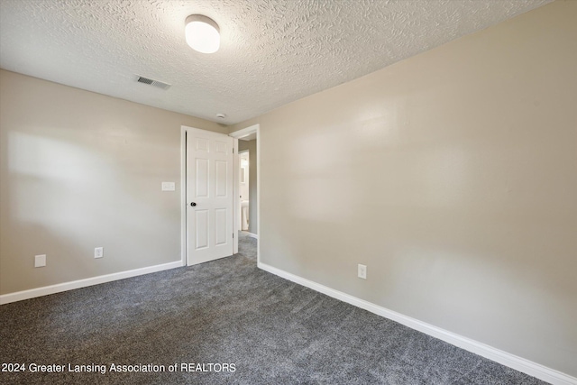 empty room featuring dark colored carpet and a textured ceiling