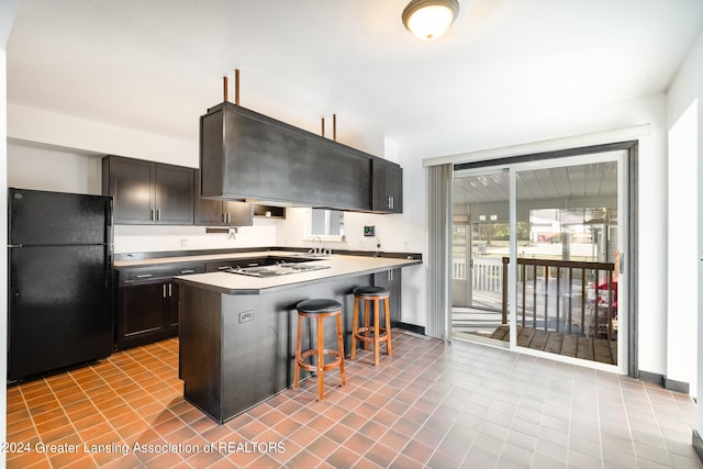 kitchen with a center island, black refrigerator, a breakfast bar area, extractor fan, and gas cooktop