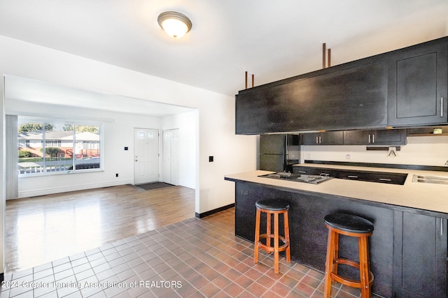 kitchen featuring a kitchen bar, sink, dark wood-type flooring, and black appliances