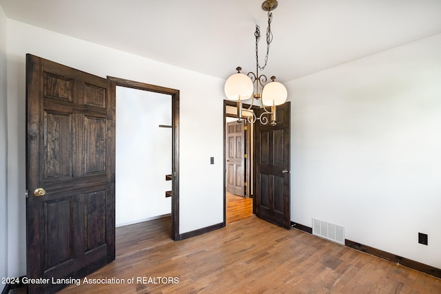 unfurnished bedroom featuring a chandelier and hardwood / wood-style flooring