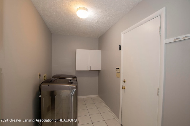 laundry room featuring washer hookup, a textured ceiling, cabinets, and light tile patterned floors