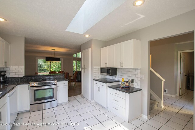 kitchen featuring stainless steel range with electric stovetop, white cabinetry, a skylight, white dishwasher, and hanging light fixtures