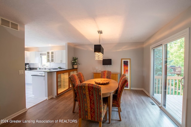 dining area featuring light wood-type flooring, a textured ceiling, and sink