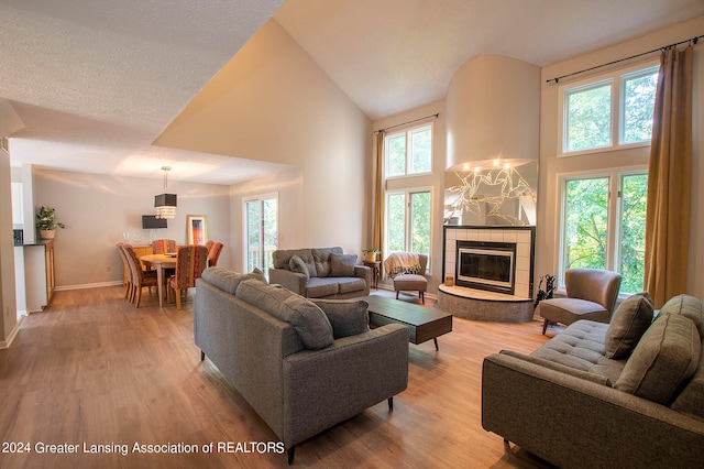 living room featuring a healthy amount of sunlight, a tiled fireplace, and light hardwood / wood-style floors