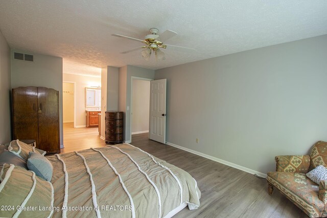 bedroom featuring ceiling fan, connected bathroom, light hardwood / wood-style floors, and a textured ceiling