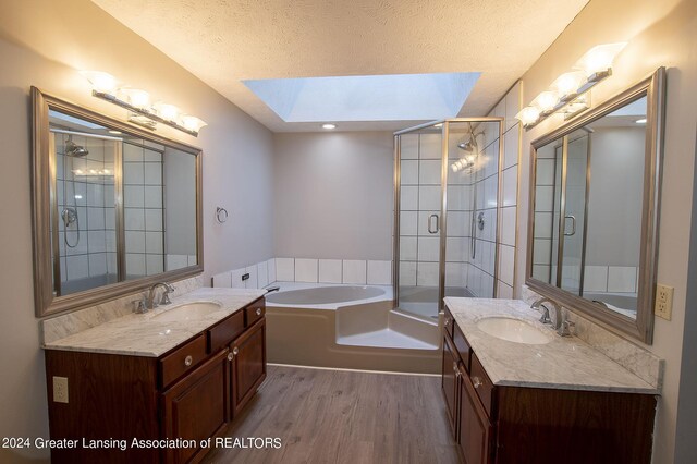 bathroom with hardwood / wood-style flooring, a textured ceiling, a skylight, and shower with separate bathtub