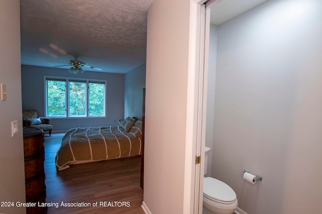 bedroom with ceiling fan, wood-type flooring, and a textured ceiling