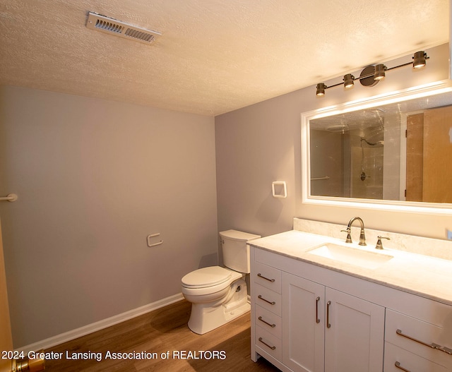 bathroom with vanity, toilet, hardwood / wood-style flooring, and a textured ceiling