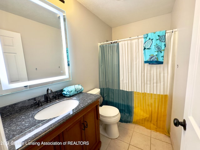 bathroom featuring tile patterned flooring, vanity, toilet, and walk in shower