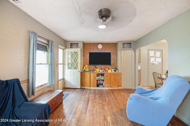 living room featuring wood finished floors, arched walkways, and a textured ceiling