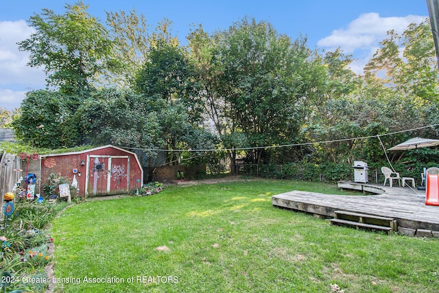 view of yard with a fenced backyard, a deck, a storage shed, and an outdoor structure