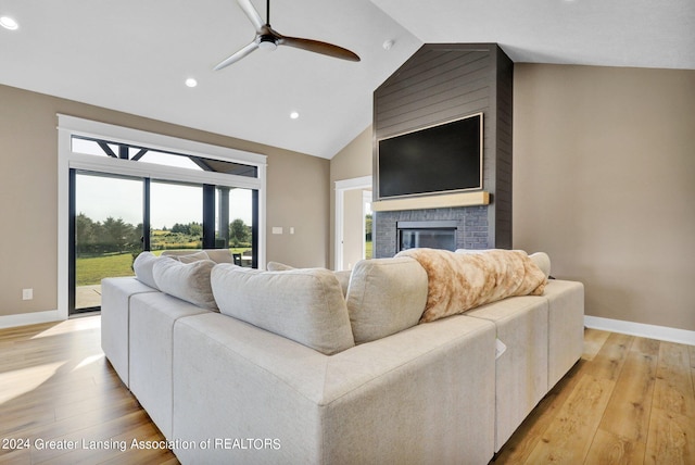 living room with lofted ceiling, ceiling fan, a fireplace, and light wood-type flooring