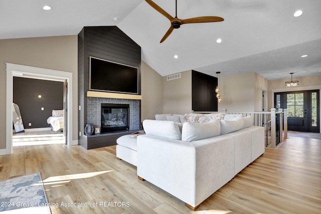 living room with a large fireplace, ceiling fan, and light hardwood / wood-style flooring