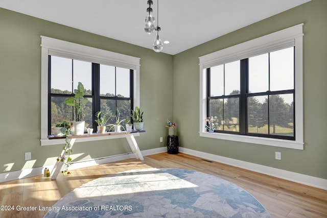 empty room with plenty of natural light, light hardwood / wood-style floors, and a notable chandelier