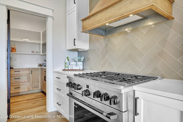 kitchen featuring white cabinets, light hardwood / wood-style floors, high end stove, and tasteful backsplash