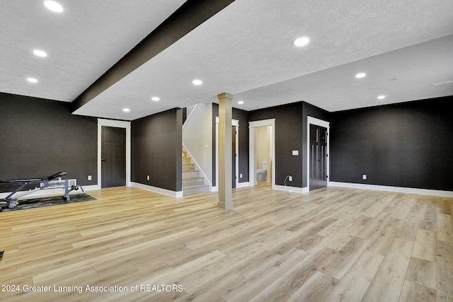 interior space with a textured ceiling, decorative columns, and light hardwood / wood-style floors