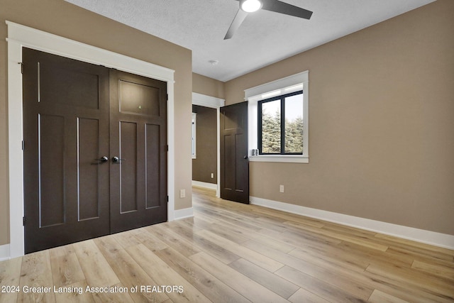 unfurnished bedroom featuring light wood-type flooring, a closet, ceiling fan, and a textured ceiling