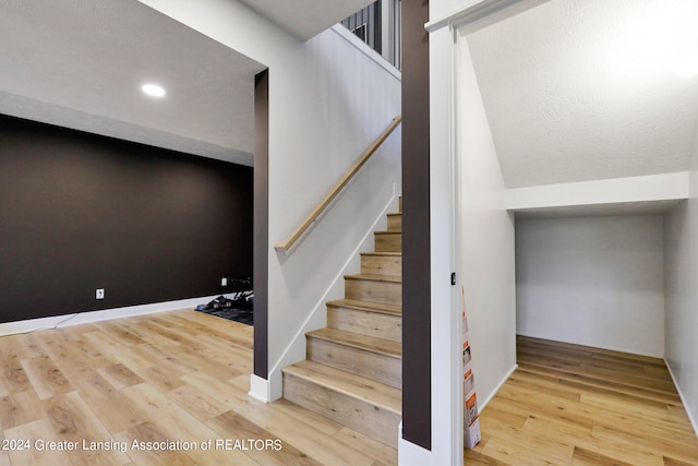 stairs with a textured ceiling and hardwood / wood-style floors